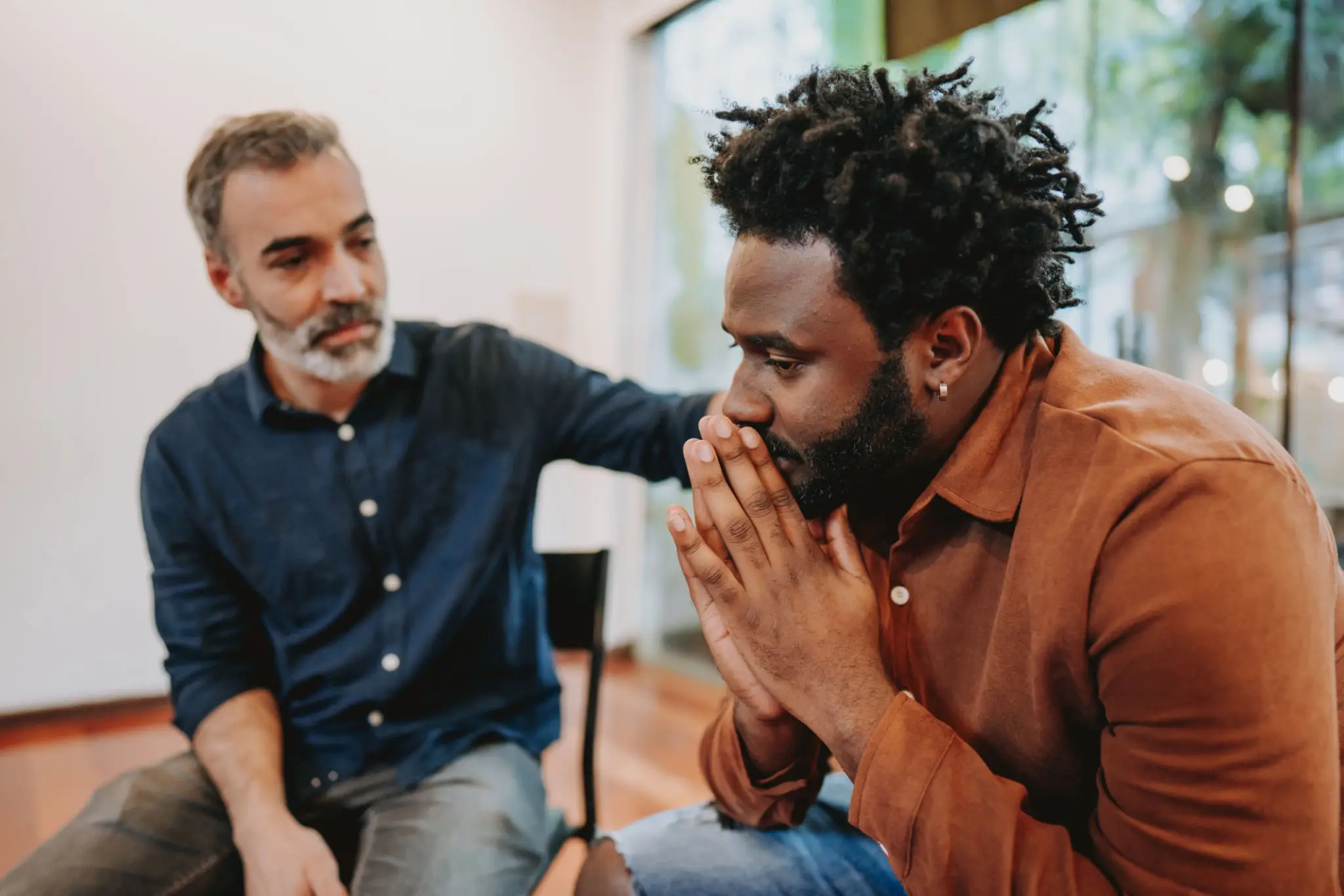 Distressed man comforted by supportive friend