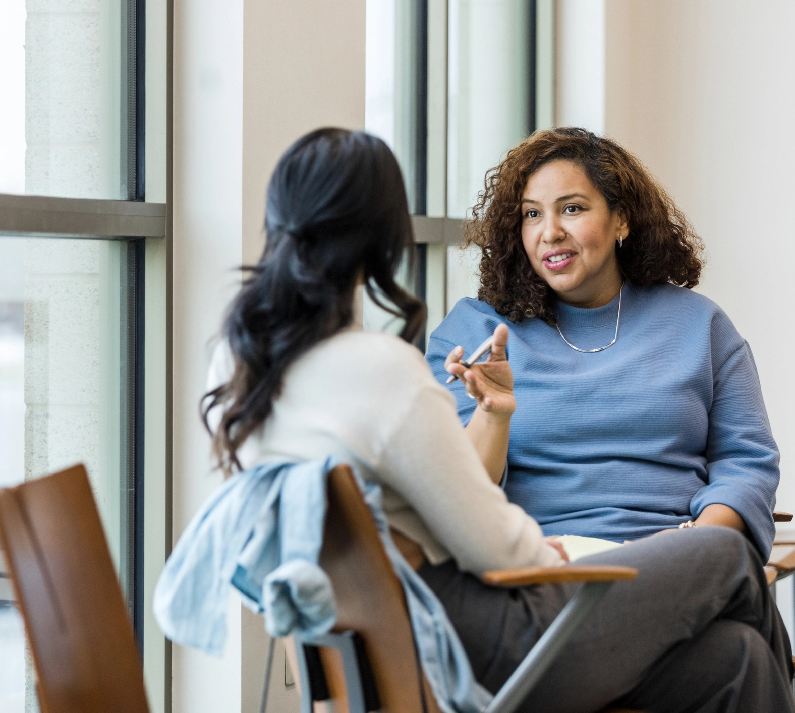 Two women talking in sunlit office