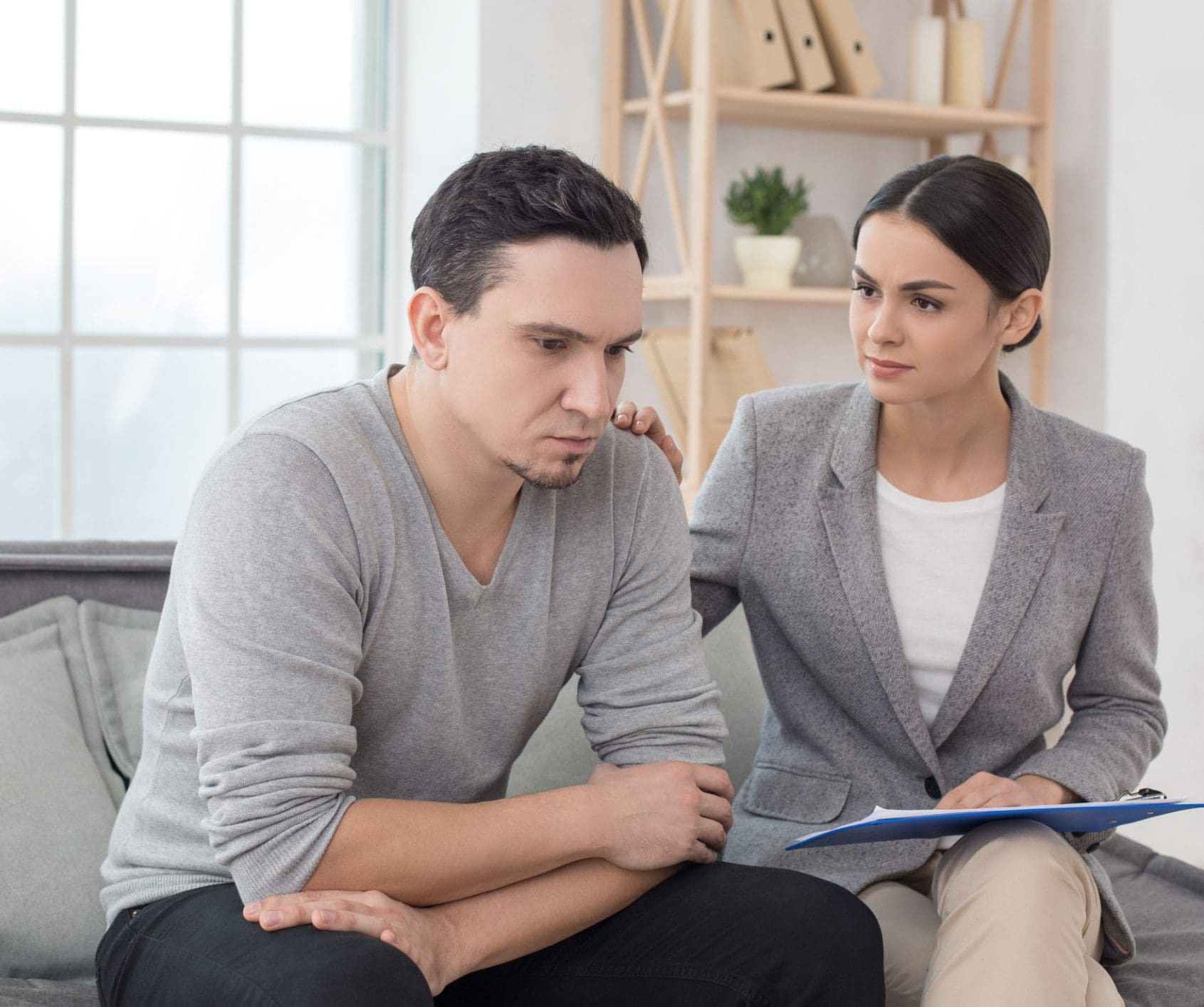 Woman comforting upset man on couch