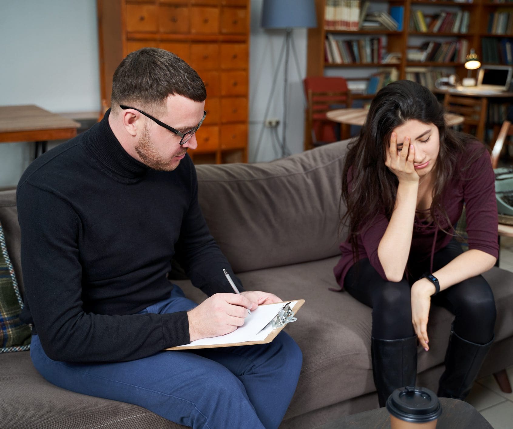 Therapist taking notes while woman looks distressed