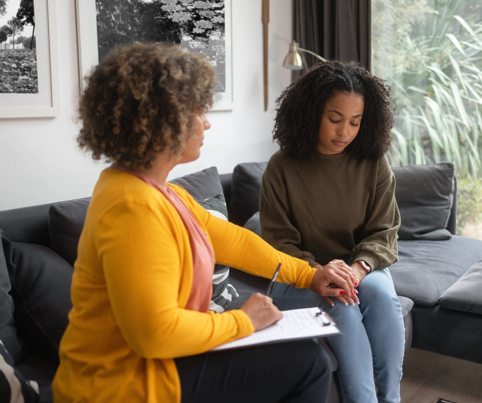 Therapist comforting young woman on couch
