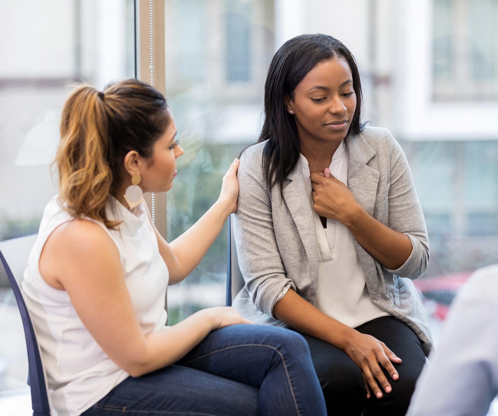 Woman consoling distressed woman in support group