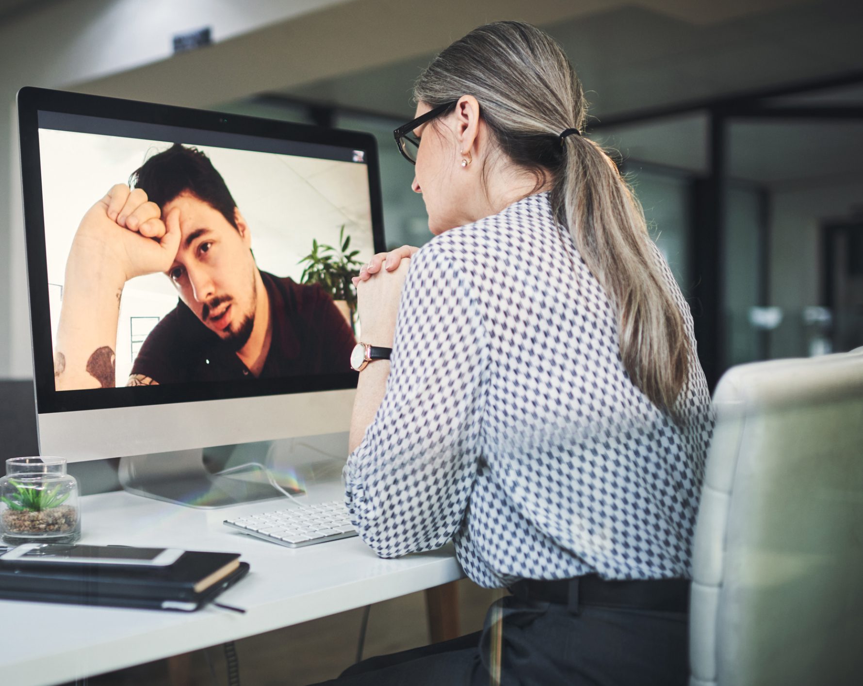 Woman video conferencing with distressed man on screen