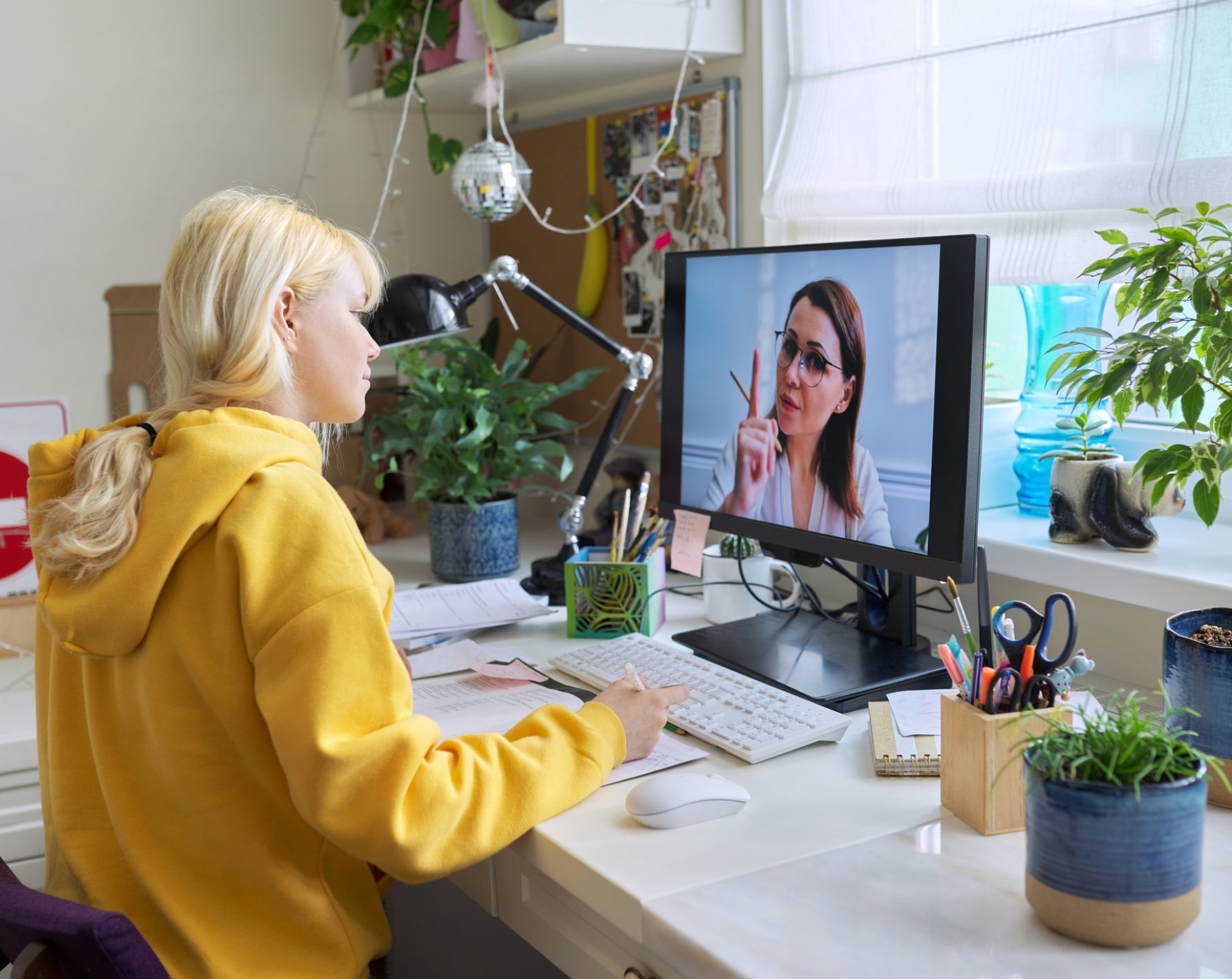 Woman video conferencing with colleague at home desk