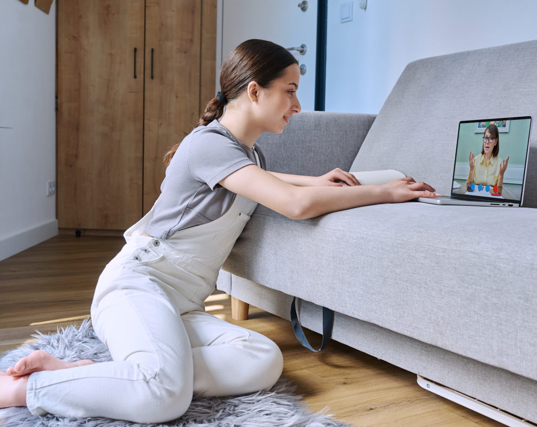 Woman kneeling watching online lesson on laptop