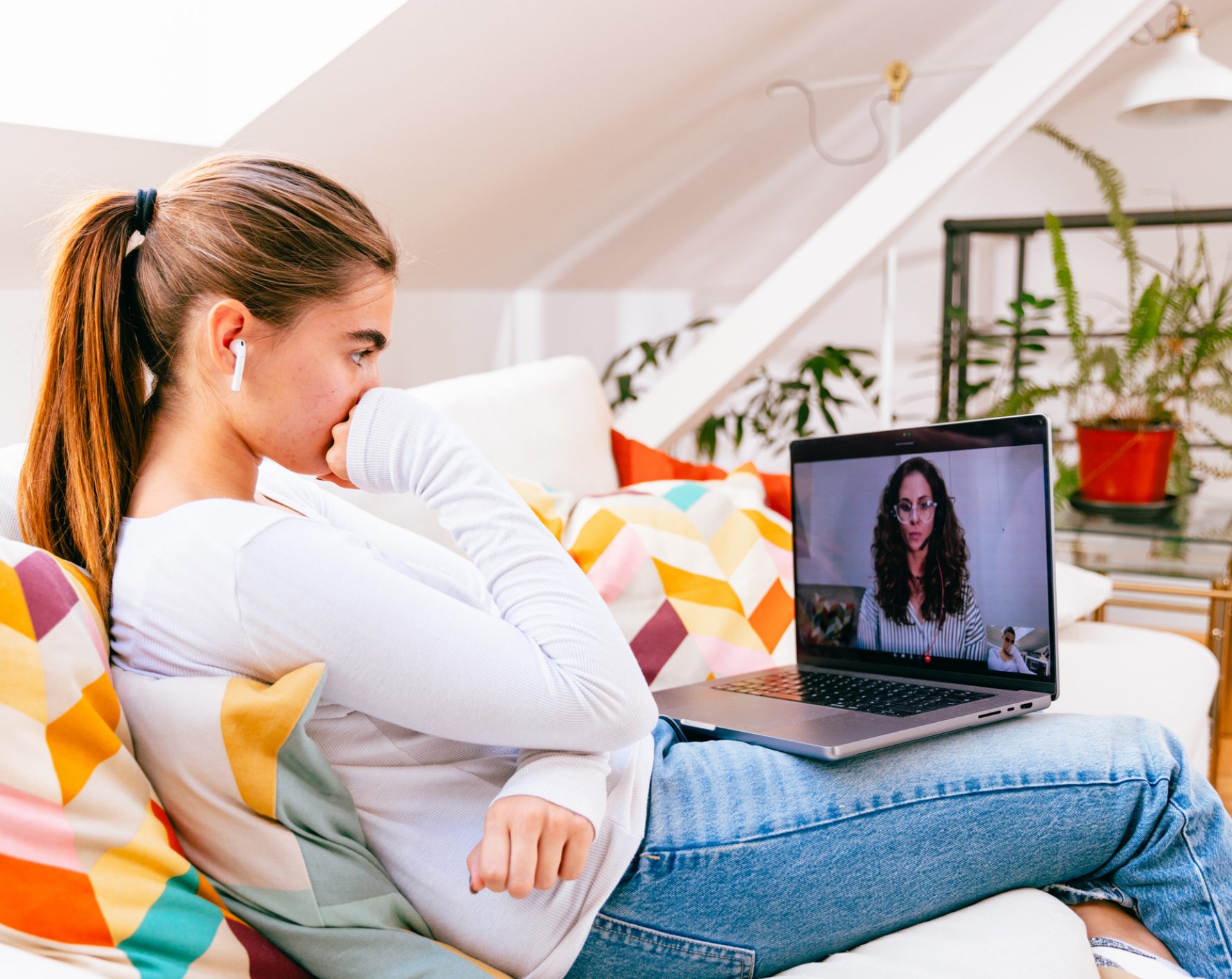 Woman on couch video-calling on laptop