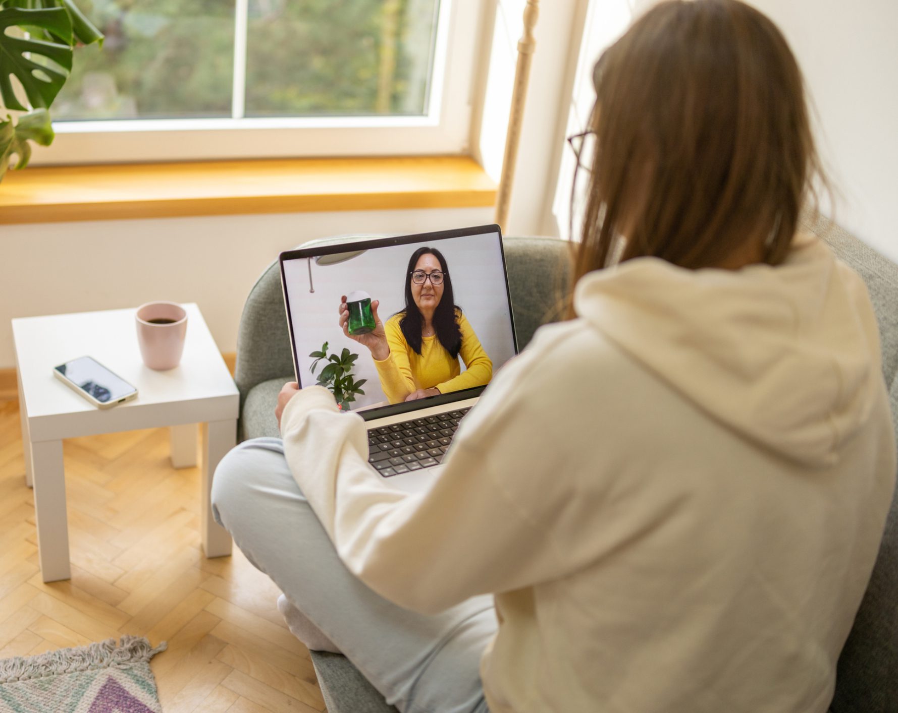 Person video chatting with woman holding plant