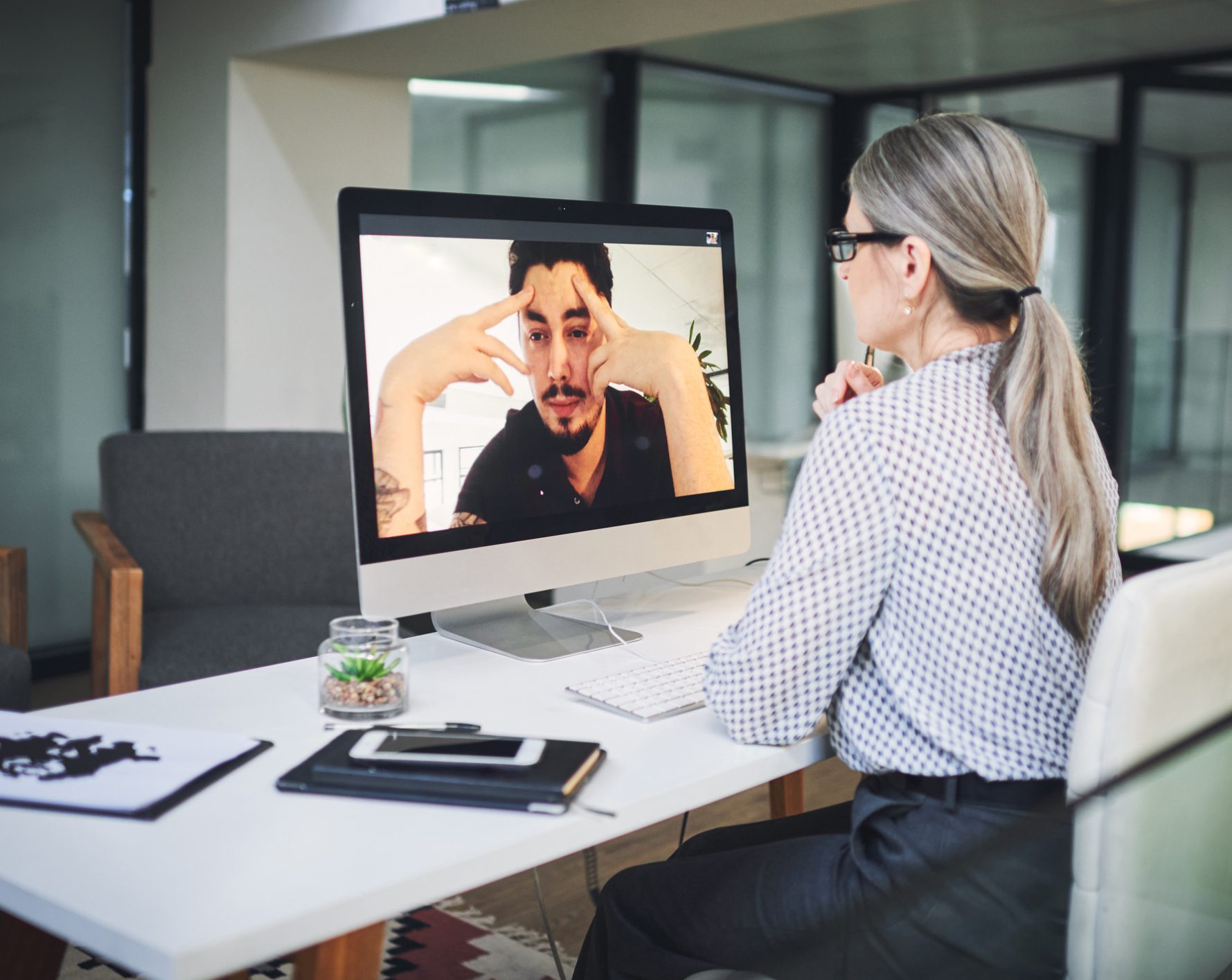 Woman video conferencing with man on desktop monitor