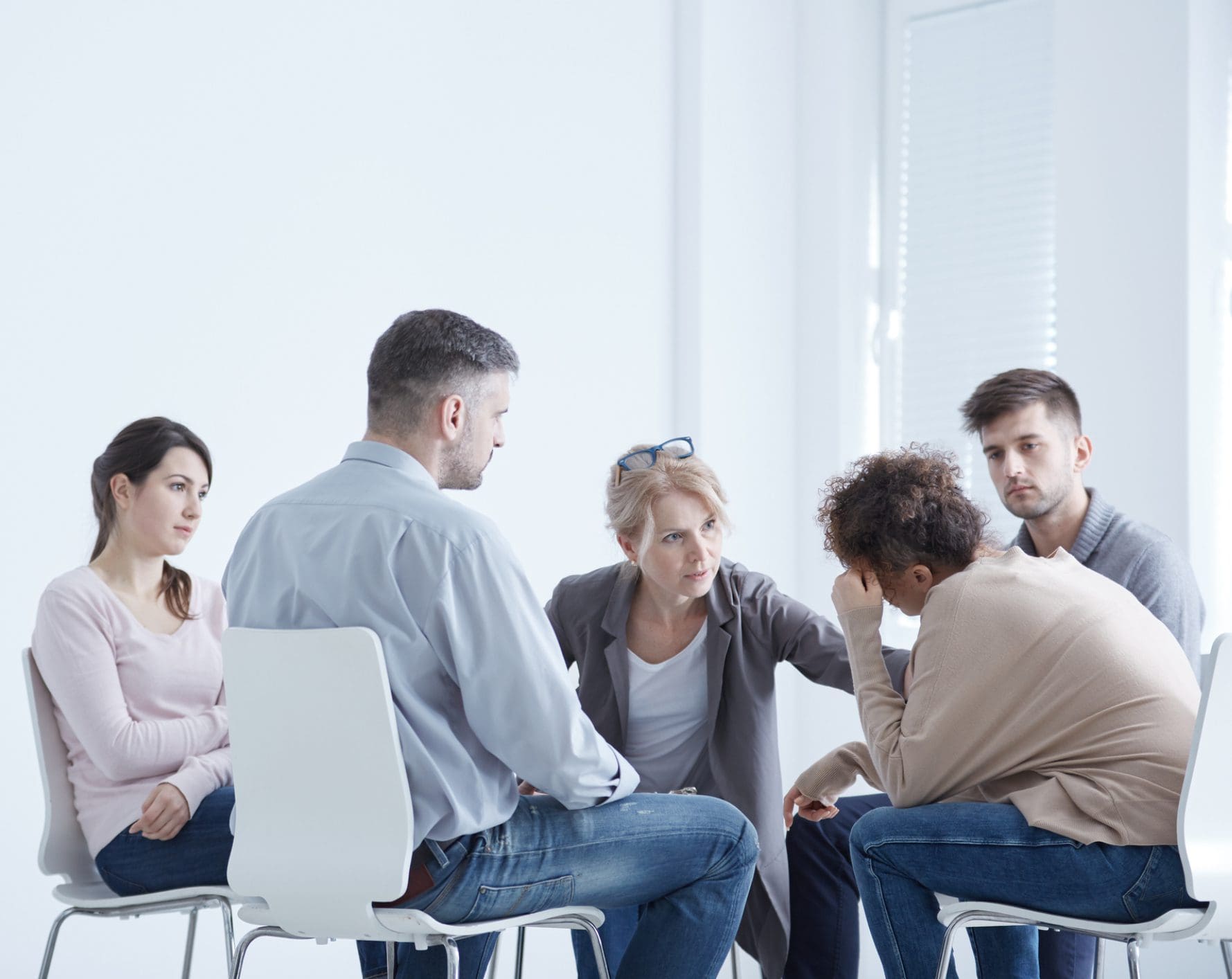 Group therapy session with counselor consoling participant