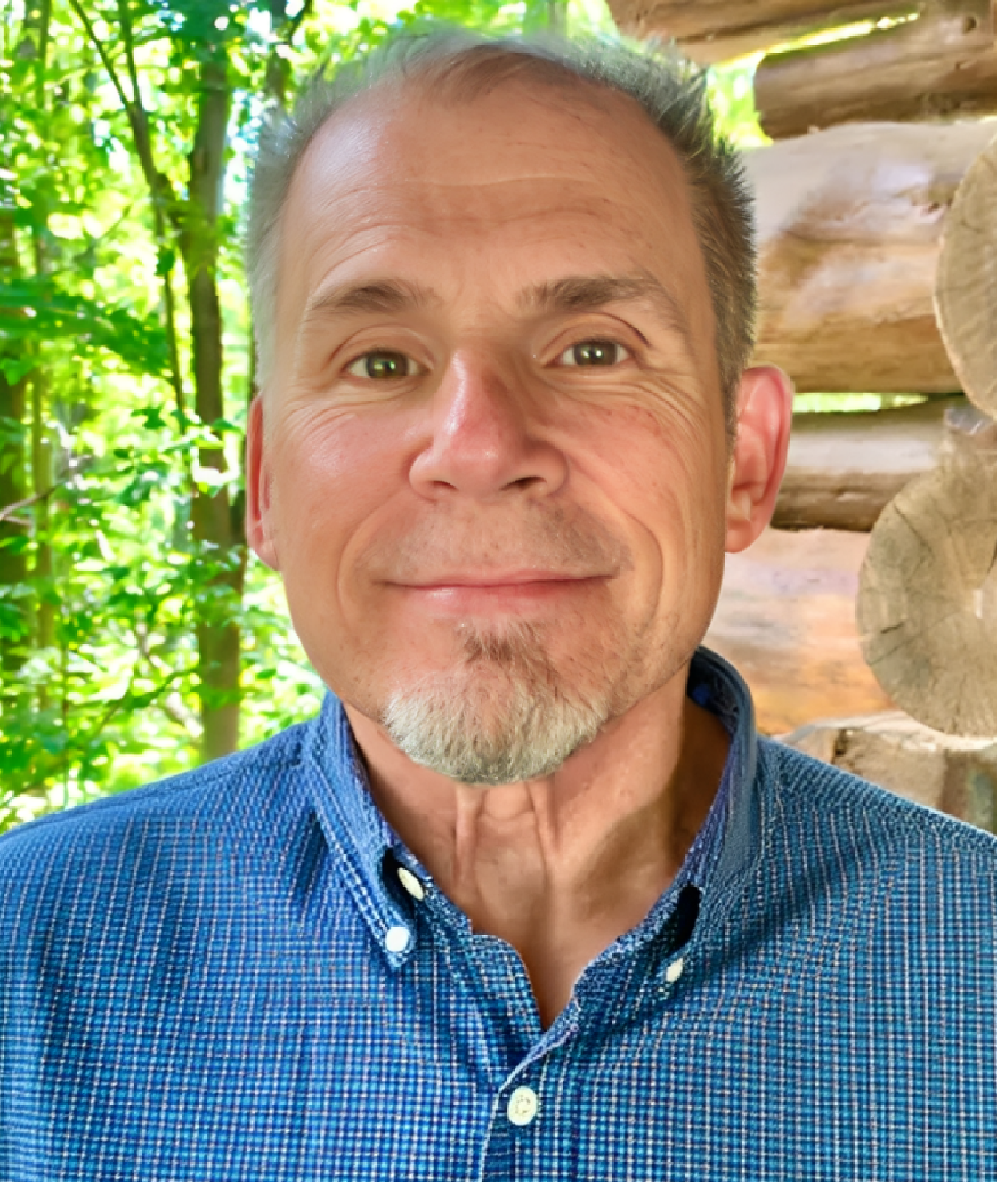 Smiling man in blue shirt by log cabin